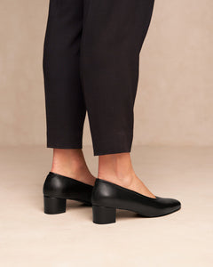 Oya Culford classic black, low heel women's shoes for extended sizes model wears shoes with black trousers. 